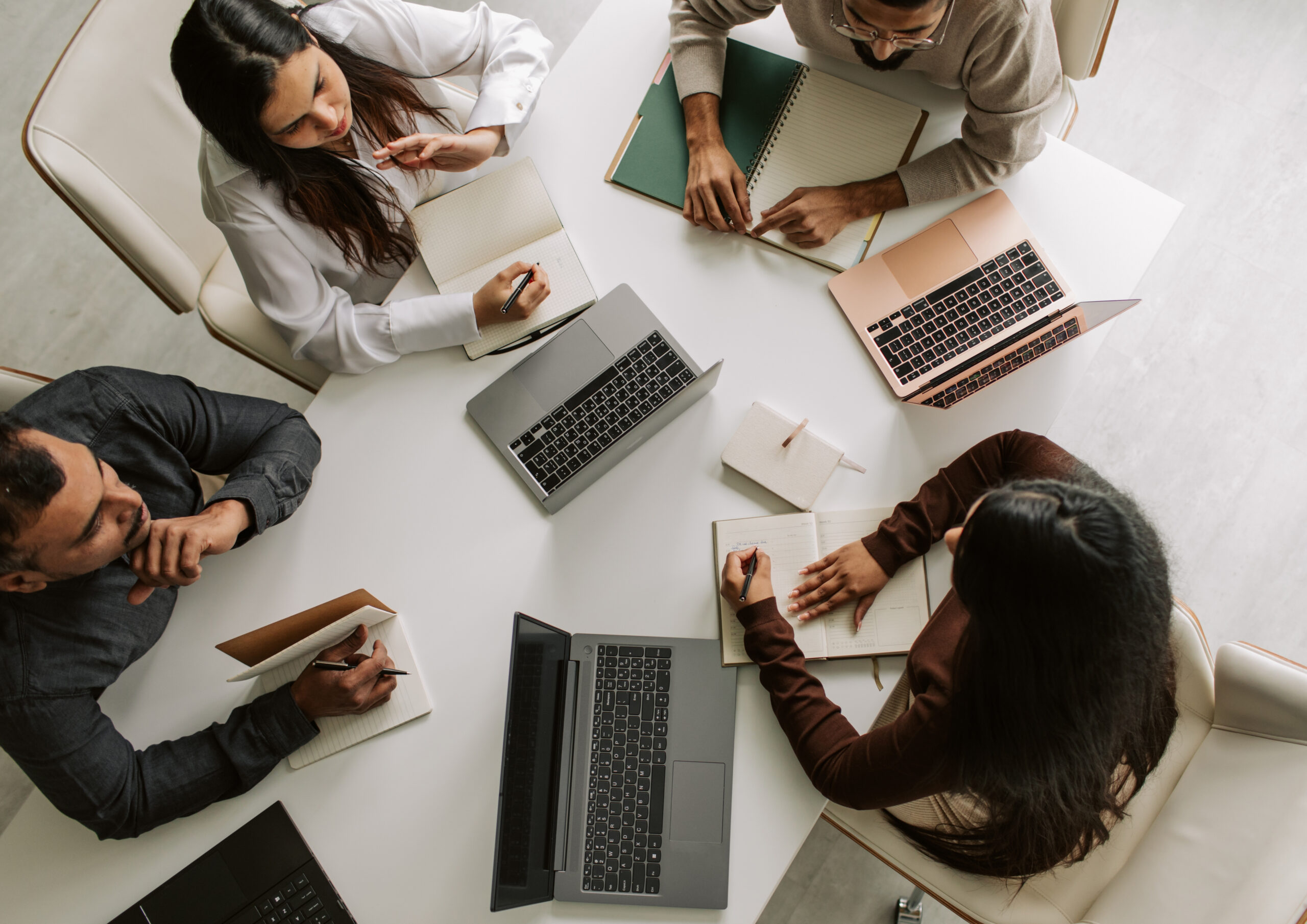 Marketing professionals collaborating around a table with laptops and notes